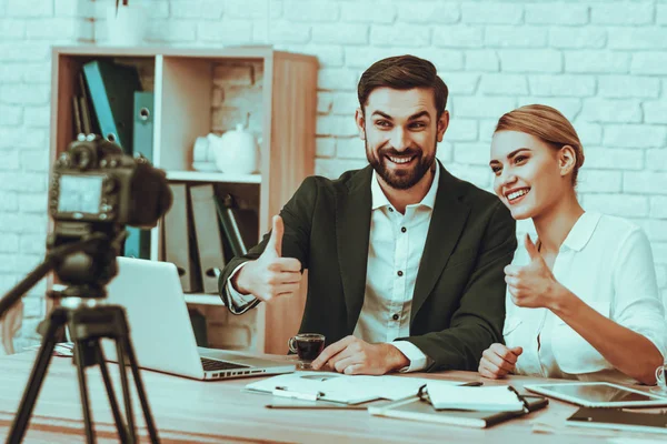 Bloggers Makes a Video. Bloggers is Young Smiling Man and Woman. Video About a Business. Camera Shoots a Video. Gadgets and Supplies on Table. People Showing OK Sign. People in Studio Interior.