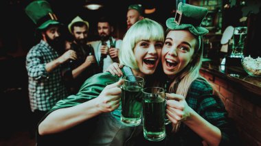 Karnaval giysili iki kız. St Patrick's Day kavramı kutlama. Bar Counter. İyi şenlikli ruh hali. Parlak ışıklar. Club ziyaretçi. Eğleniyor. Birlikte dinleniyor. Cam bira içmek.