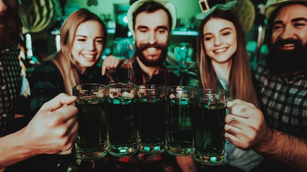 Young Company Are Celebrating St Patrick's Day. Bar Counter. Alcohol Handling. Black Beard. Smiling Teenagers. Good Festive Mood. Bright Lights. Club Visitors. Funny Hats. Glasses With Beer Clinking.