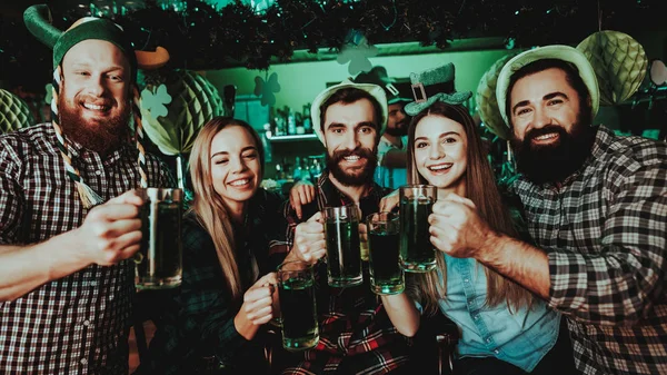 Young Company Are Celebrating St Patrick\'s Day. Bar Counter. Alcohol Handling. Black Beard. Smiling Teenagers. Good Festive Mood. Bright Lights. Club Visitors. Funny Hats. Glasses With Beer.