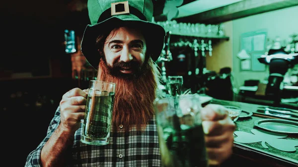 Guy In The Leprechaun Cap Is Drinking A Beer. Bar Counter. Alcohol Handling. Black Beard. Smiling Male. Good Festive Mood. Bright Lights. Funny Club Visitor. Open Mouth. St Patrick's Day.