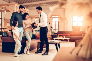 Genç aile mobilya satıcı ile danışmanlık. Mutlu birlikte. Parlak Office. Güneşli Day.Manager gömlek ve kravat. İş görüşmesi. Oda iç. Anne ve kızı. Mağaza bak.