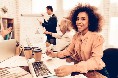 İş ve finans okuyan öğrenciler. Yeni bilgi gösteren öğrencilere öğretmendir. Öğrenciler farklı yaş çok ırklı insanlar var. Siyah kadın öğrenci bir kameraya bakıyor. Sınıf insanlarda.
