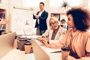 İş ve finans okuyan öğrenciler. Soru soran öğretmendir. Erkek öğrenci bir cevap var. Diğer öğrencilerin birbirleriyle Talking olduğunu. Öğrenciler farklı yaş çok ırklı insanlar var. Sınıf.