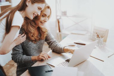 Anne ve kızı dizüstü evde izliyor. Kızı yardımcı anne. Anne ve kızı evde. Genç kız. Frilancing anne kavramı. Dijital aygıt kullanarak kadınlar. Gülümseyen kadın.