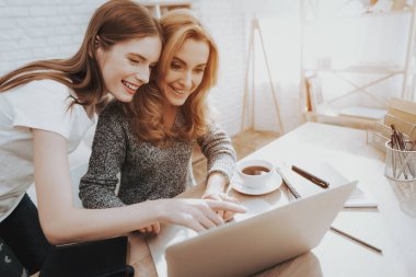 Anne ve kızı dizüstü evde izliyor. Kızı yardımcı anne. Anne ve kızı evde. Genç kız. Frilancing anne kavramı. Dijital aygıt kullanarak kadınlar. Gülümseyen kadın.