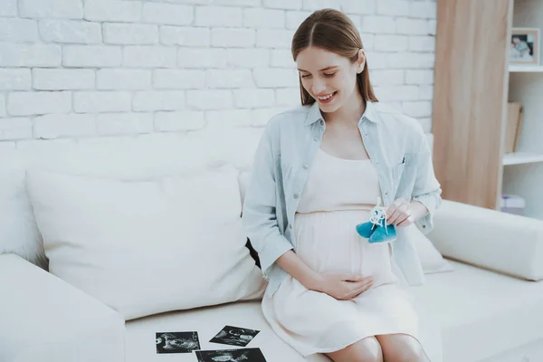 怀孕的年轻女子持有鞋新生儿 快乐的母亲概念 健康怀孕的概念 年轻的母亲 肚皮上的小鞋子 期待新的生活 产妇概念 微笑的女孩 — 图库照片