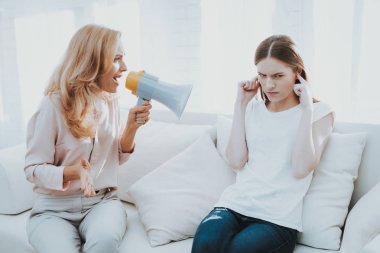 Anne ve kızı beyaz odada arasında kavga. Duygusal tartışma. Kanepede oturan. Aile çatışmada. Üst ve alt. Mutsuz kız. İletişim kavramı. İlişkimde sorunlar.