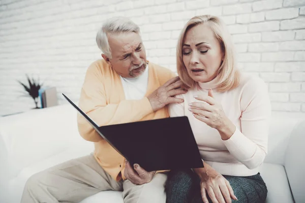 Old Man near Old Woman with Documents in Black Folder. Important Documents. Sitting on White Sofa. Grandfather and Grandmother. Family at Home. Reading Documents. People with Gray Hair.