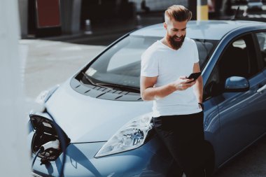 Tesla araba şarj kavramı. Adam telefon arka plan üzerinde konuşma ile. Otomobil istasyonu. Yenilik teknoloji. Yeni nesil Electro hibrid araç eklenti. Ekoloji istasyonu. Futuristik güç.