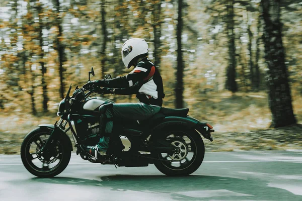 戴头盔的骑自行车的人骑在森林里的公路上 速度车 穿着皮夹克的骑手很酷 摩托车概念 经典风格 准备开车了在森林里速骑摩托车 隐藏的面孔 — 图库照片