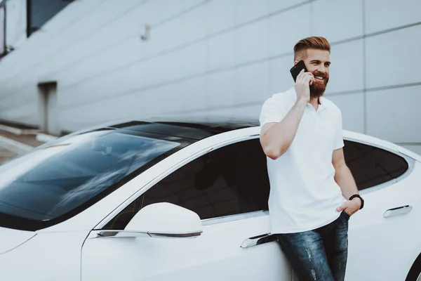 Man Talks On Phone Near Tesla Car. Charge Station. Automobile Parking Lot. Innovation Technology. New Generation Electro Hybrid Vehicle. Ecology Station. Futuristic Power. Gadget Concept.