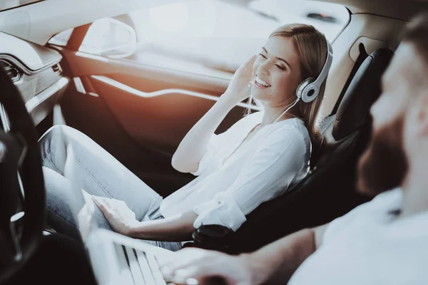 人工作与笔记本电脑 戴耳机的女孩特斯拉汽车前排座位 创新技术 新一代电动混合动力车 奢华设计 未来的力量 Resring 在一起 测试驾驶 — 图库照片