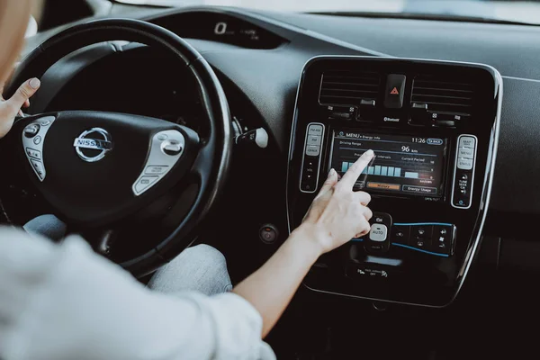 テスラ車の女性 背後にあるホイールのコンセプト 革新技術 新世代電気ハイブリッド車 豪華なデザイン 未来の力 ディスプレイに手します 内部ビュー フロント シート — ストック写真