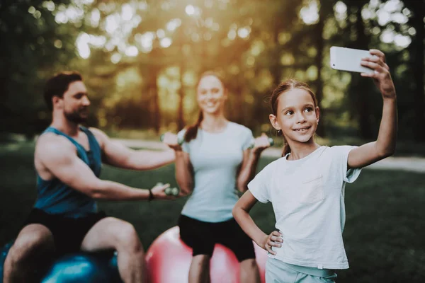 Familia joven feliz usando la tableta en el parque de verano . — Foto de Stock