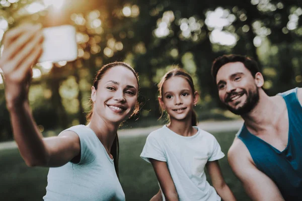Familia joven feliz usando la tableta en el parque de verano . — Foto de Stock