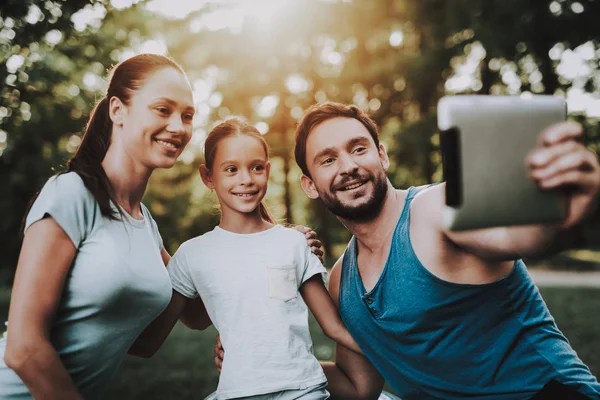 Ευτυχισμένη οικογένεια νέους χρησιμοποιώντας Tablet στο πάρκο καλοκαίρι. — Φωτογραφία Αρχείου