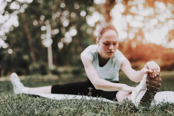Mujer joven en ropa deportiva haciendo yoga en el parque . — Foto de Stock