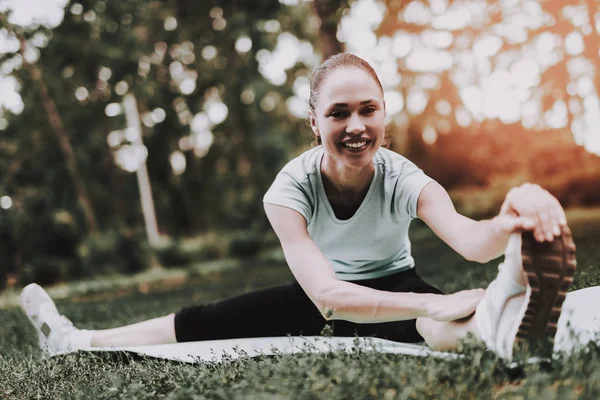 Mujer joven en ropa deportiva haciendo yoga en el parque . — Foto de Stock