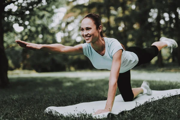 Mujer joven en ropa deportiva haciendo yoga en el parque . — Foto de Stock