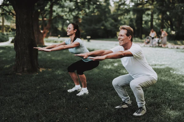 Ungt par i sportkläder gör övningar i Park — Stockfoto