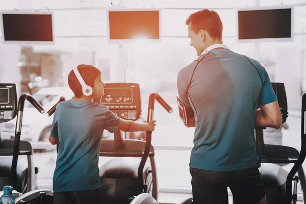 Young Father and Son Training on Treadmills in Gym