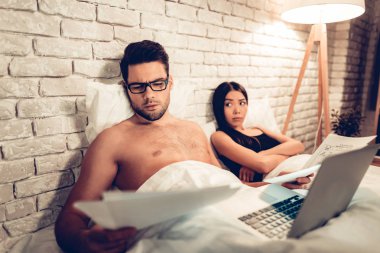 Genç çift yatakta, Laptop Bored eşi çalışan adam