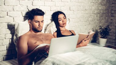 Uyumadan önce Laptop okuma kitabı kullanarak çift