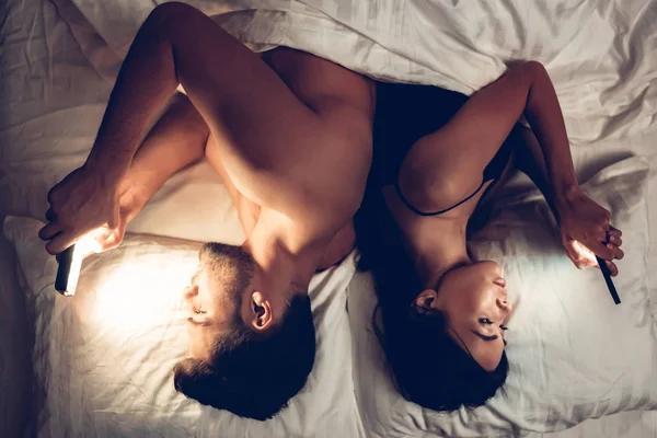 Δυο ερωτευμένοι στο κρεβάτι, χρήση κινητού τηλεφώνου το βράδυ — Φωτογραφία Αρχείου