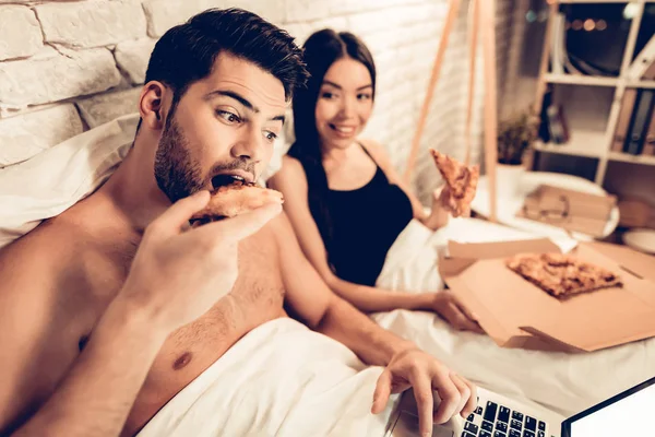 Loving Couple Watching Movie Eating Pizza in Bed