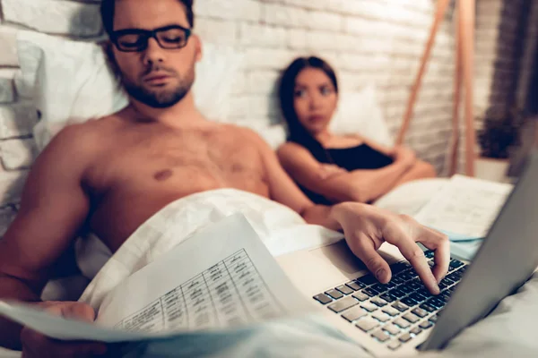 Pareja joven en la cama, Hombre Trabajando Esposa aburrida portátil —  Fotos de Stock