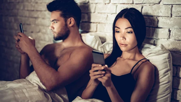 Pár v lásce v posteli pomocí mobilního telefonu v noci — Stock fotografie