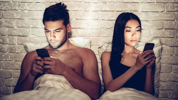 Verliebtes Paar nachts mit Handy im Bett — Stockfoto