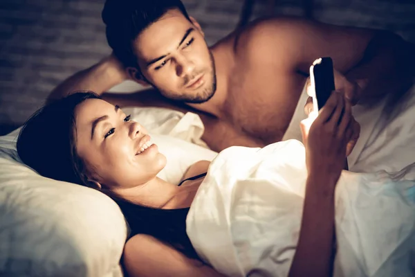 Pár v lásce v posteli, dívka pomocí mobilního telefonu — Stock fotografie