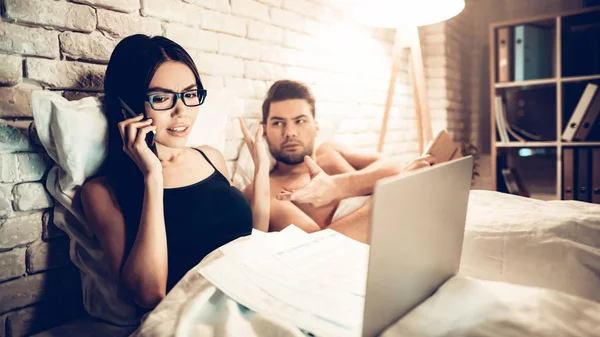 Pareja joven en la cama, Chica que trabaja el hombre aburrido portátil —  Fotos de Stock