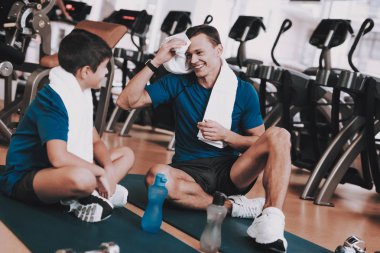 Genç baba ve oğul paspaslar spor kulübü içinde oturan. Sağlıklı yaşam konsepti. Spor ve eğitim kavramları. Modern spor kulübü. Spor donatımı. Aile spor. Eğitimden sonra dinlenme. Anne-baba ile çocuk.