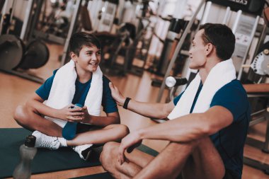 Genç baba ve oğul paspaslar spor kulübü içinde oturan. Sağlıklı yaşam konsepti. Spor ve eğitim kavramları. Modern spor kulübü. Spor donatımı. Aile spor. Eğitimden sonra dinlenme. Anne-baba ile çocuk.