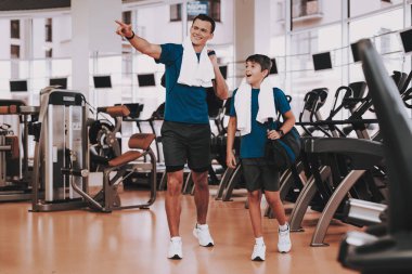 Genç baba ve oğul Modern spor salonunda koşu bandı yakınındaki. Sağlıklı yaşam konsepti. Spor ve eğitim kavramları. Modern spor kulübü. Spor donatımı. Aile spor. Koşu izler. Anne-baba ile çocuk.
