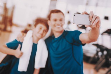 Genç baba ve oğlu Selfie Modern spor salonunda koşu bandı yakınındaki alarak. Sağlıklı yaşam konsepti. Spor ve eğitim kavramları. Smartphone kullanarak. Aile spor. Koşu izler. Anne-baba ile çocuk.