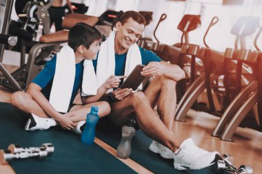 Genç baba ve oğul paspaslar spor kulübü içinde oturan. Sağlıklı yaşam konsepti. Spor ve eğitim kavramları. Modern spor kulübü. Spor donatımı. Aile spor. Eğitimden sonra dinlenme. Anne-baba ile çocuk.