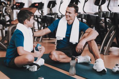 Genç baba ve oğul paspaslar spor kulübü içinde oturan. Sağlıklı yaşam konsepti. Spor ve eğitim kavramları. Modern spor kulübü. Spor donatımı. Aile spor. Eğitimden sonra dinlenme. Anne-baba ile çocuk.