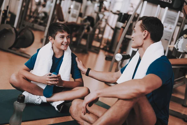 Young Father and Son Sitting on Mats in Sport Club. Healthy Lifestyle Concept. Sport and Training Concepts. Modern Sport Club. Sport Equipment. Family Sport. Rest after Training. Parent with Child.