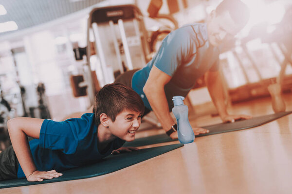 Young Father and Son Doing Exercises in Sport Club. Healthy Lifestyle Concept. Sport and Training Concepts. Modern Sport Club. Sport Equipment. Family Sport. Running Tracks. Parent with Child.
