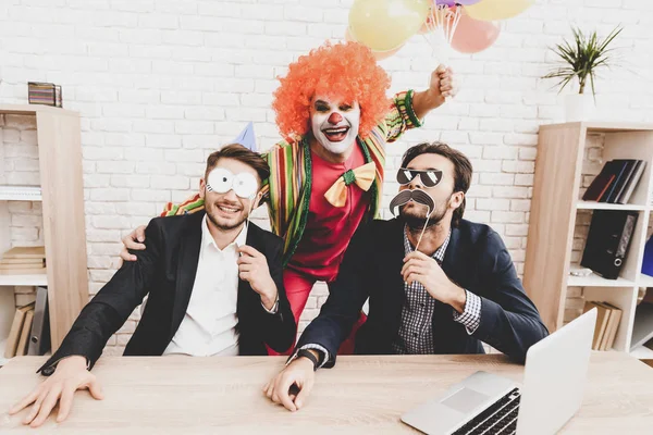 Young Man in Clown Costume on Meeting in Office. April Fools Day. Businessman in Office. April Jokes. Workers on Meeting. Holidays and Celebration Concept. Clown with Baloons. Man with Red Nose.