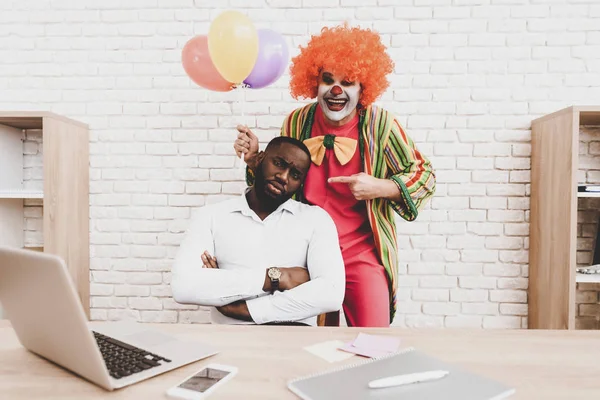 Young Man in Clown Costume with Baloons in Office. April Fools Day. Businessman in Office. April Jokes. Workers on Meeting. Holidays and Celebration Concept. Clown with Baloons. Man with Red Nose.