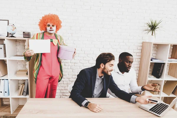 Young Man in Clown Costume on Meeting in Office. April Fools Day. Businessman in Office. April Jokes. Crazy Day. Workers on Meeting. Holidays and Celebration Concept. Clown with Red Nose.