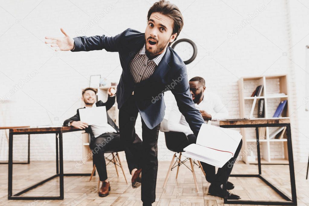 Suprized Young Man Kicked by Colleagues in Office. April Fools Day. Businessman in Office. April Jokes. Crazy Day. Laptop in Office. Holidays and Celebration Concept. Jokes in Office.