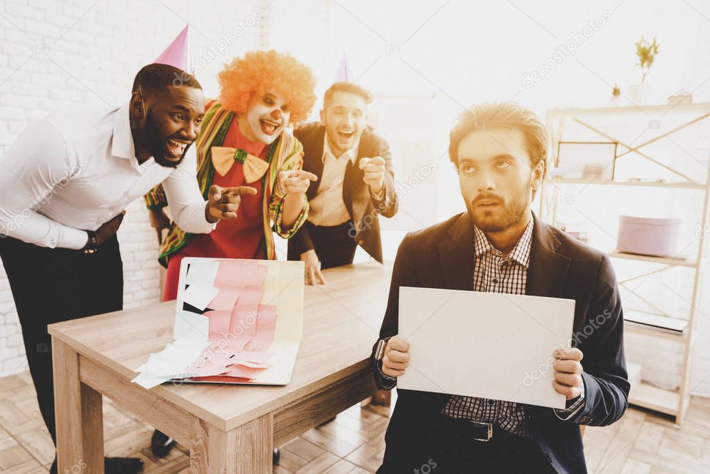 Young Man in Clown Costume on Meeting in Office. April Fools Day. Businessman in Office. April Jokes. Stickers on Laptop Workers on Meeting. Holidays and Celebration Concept. Clown with Red Nose.