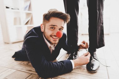Adam yerde yatıyor ve arkadaşınızın ayakkabı bağcığı bağlama. Ofiste iş görüşmesi. Nisan bir gün. Ofiste iş adamı. Nisan şakaları. Tatiller ve kutlama kavramları. Ofis şakalar.