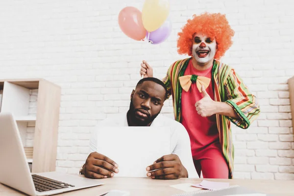 Young Man in Clown Costume with Baloons in Office. April Fools Day. Businessman in Office. April Jokes. Workers on Meeting. Holidays and Celebration Concept. Clown with Baloons. Man with Red Nose.
